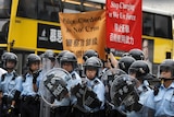 Police in riot gear near signs saying 'stop charging or we use force'.