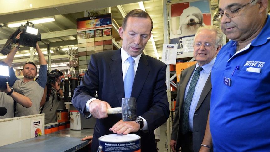 Tony Abbott makes sure the lid is on after trying his hand at paint mixing at a hardware store in Matraville.