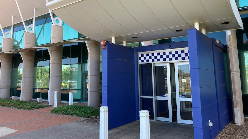 The exterior of a police station with blue and white checks above doors.