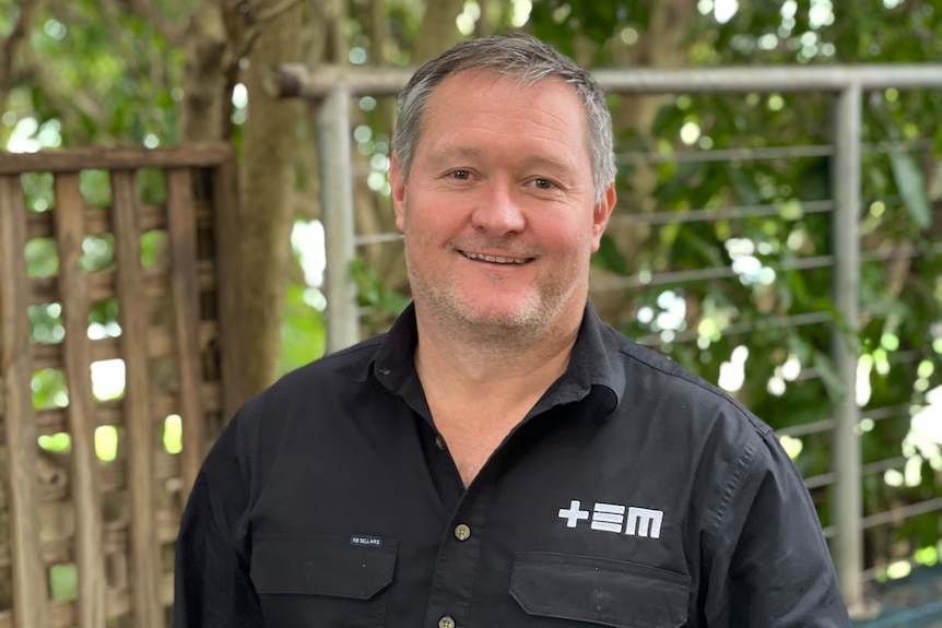 Man smiles at camera with black shirt on