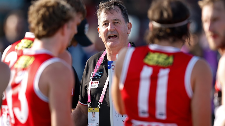 Ross Lyon speaks to a group of St Kilda players during a break in play