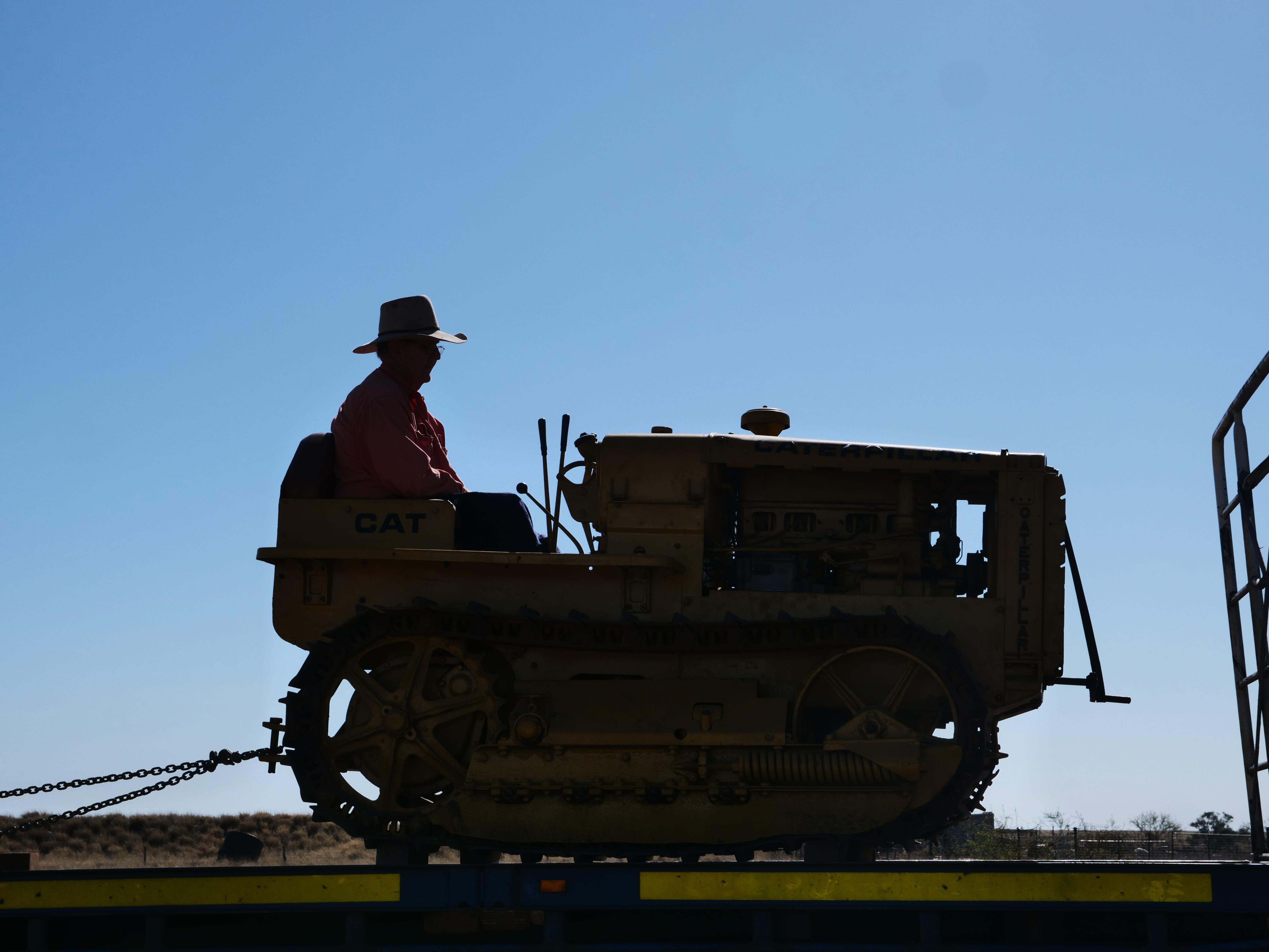 a silhouette of a man sitting on a small tractor
