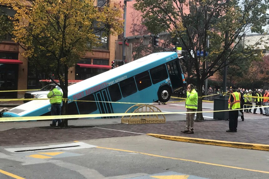 police tape sections off the area where a bus has fallen into a sinkhole