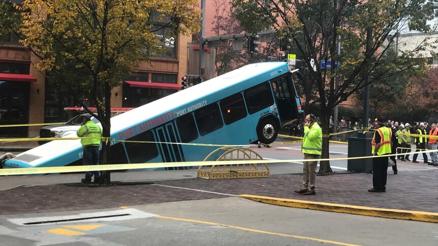 police tape sections off the area where a bus has fallen into a sinkhole