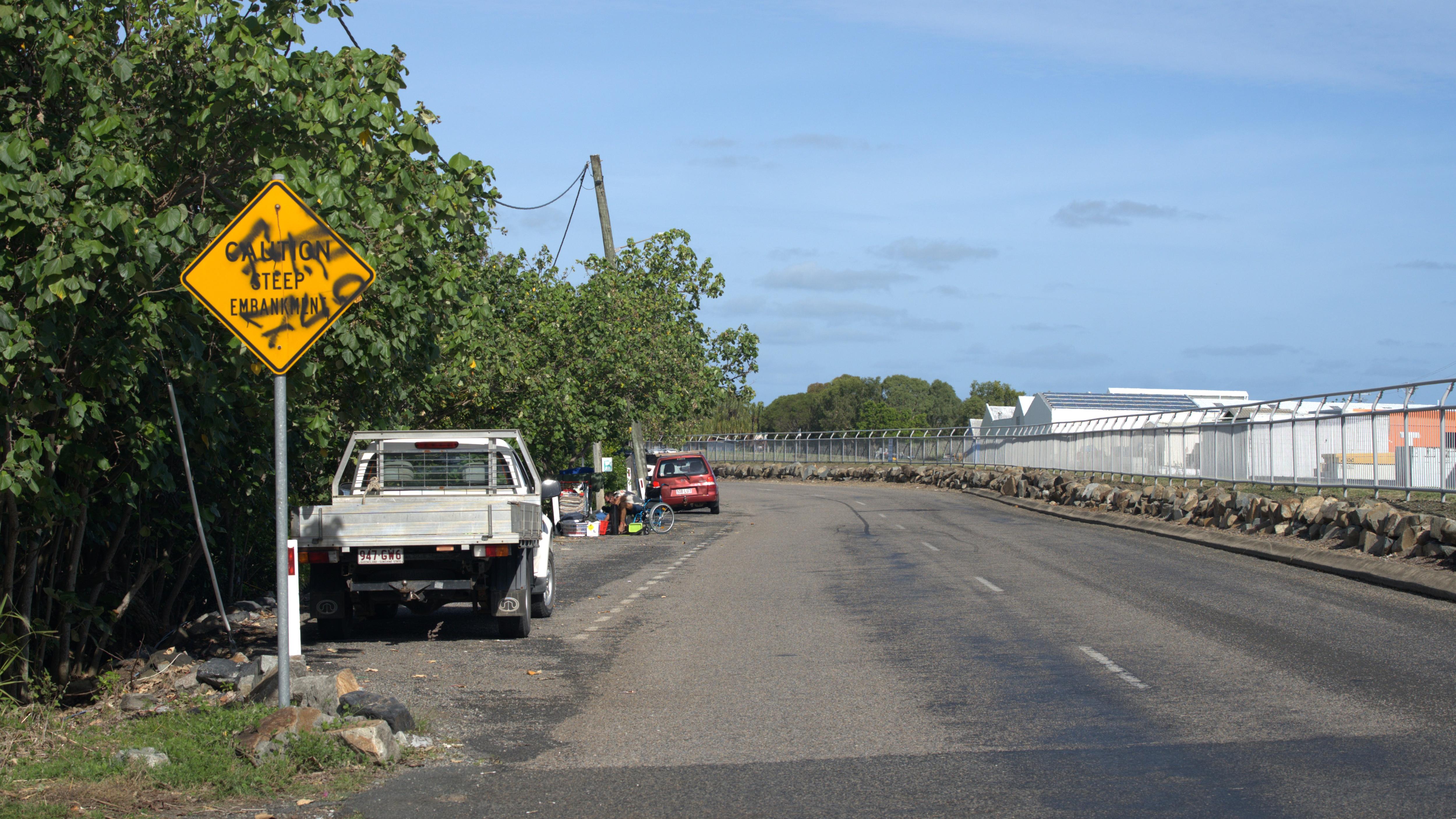 Propiedad y campings a lo largo de una pared rocosa con un río al fondo y una carretera en primer plano.