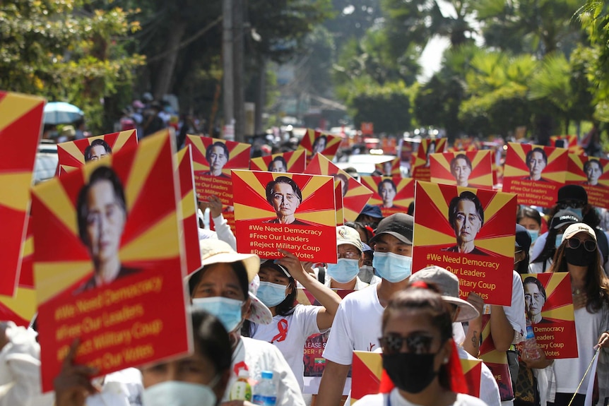 A huge crowd of protester hold posters with an image of a woman on a yellow and red background with various political messages