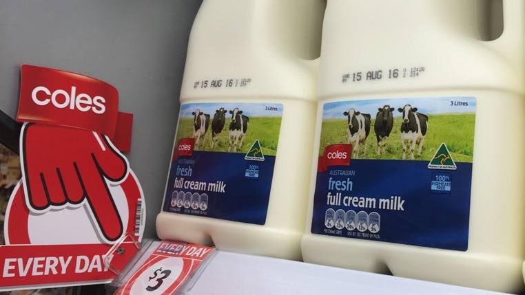 big bottles of milk sit on a shelf with a tag indicating the price is very low.