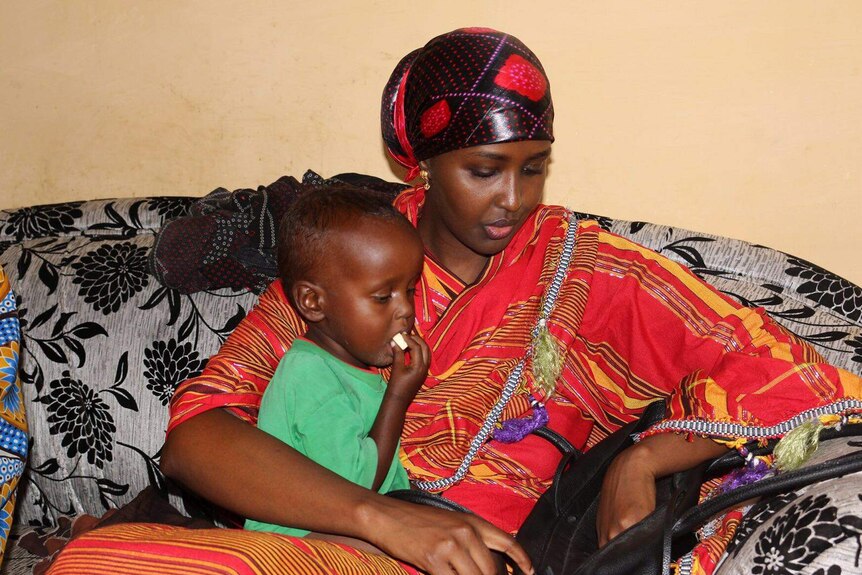 Fadumo Dayib, Somali presidential candidate sitting on a couch and holding a child.