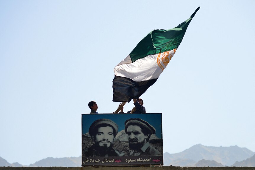 Two men wave an previous flag of Afghanistan, which represents the resistance movement. 
