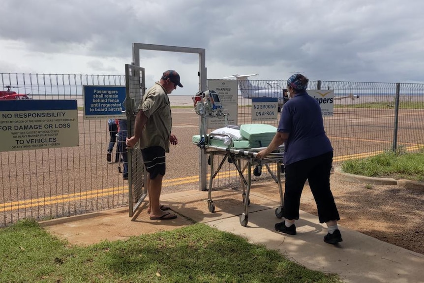 A health worker wheels a gurney towards a remote airstrip