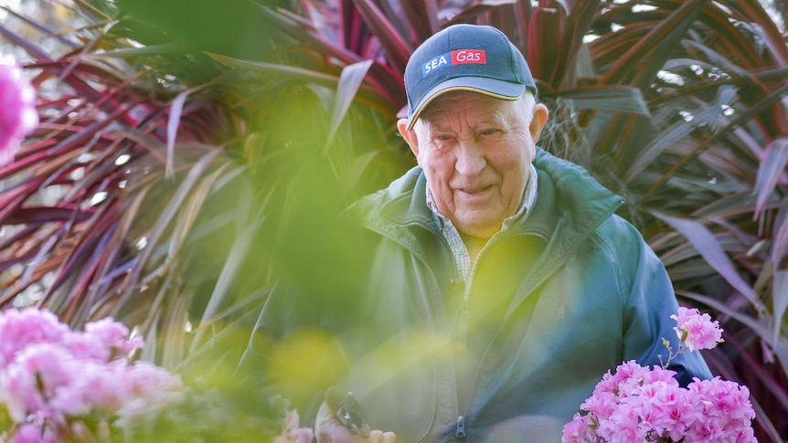 Jimmy Thomson surrounded by flowers and foliage in his garden.