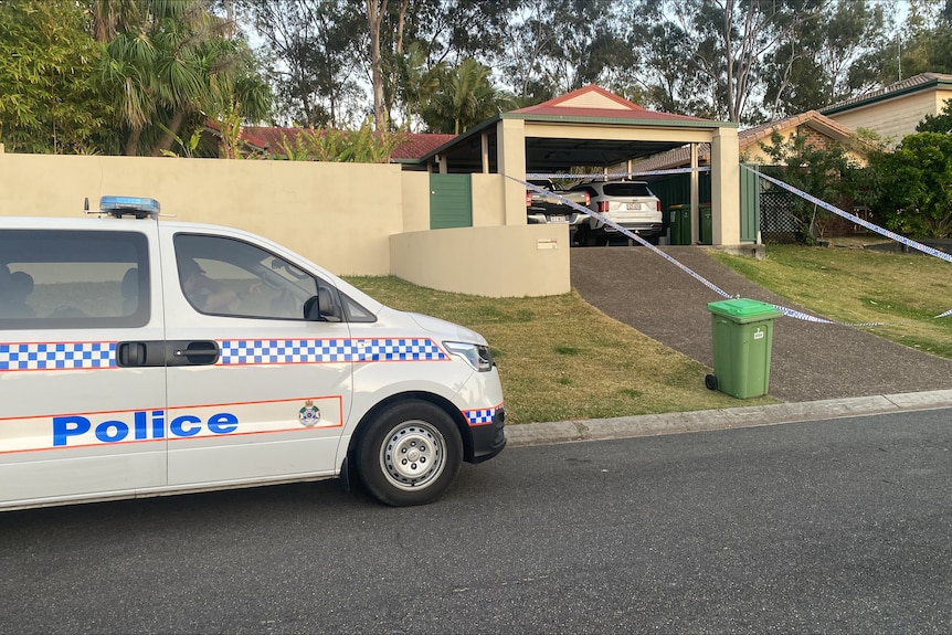 Police tape and a police van outside a house.