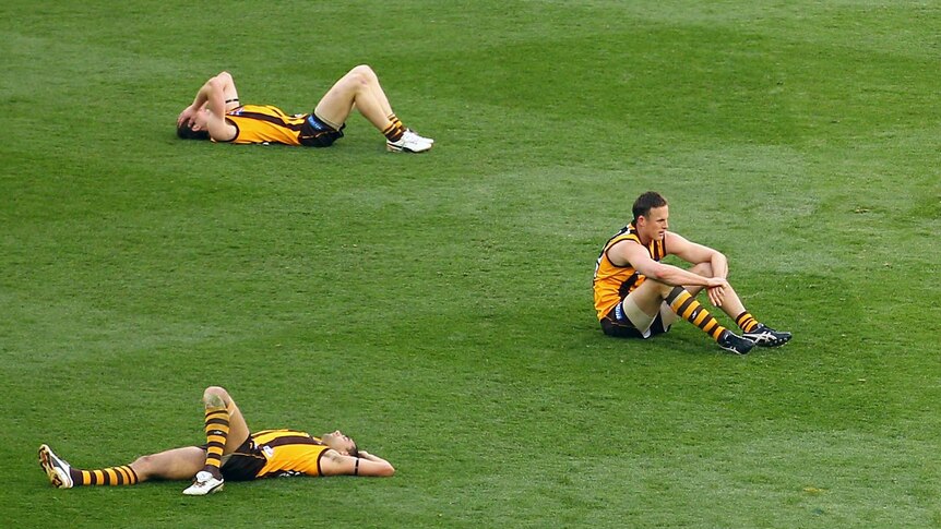 Hawthorn players lie on the MCG after losing the 2012 AFL grand final to the Sydney Swans.