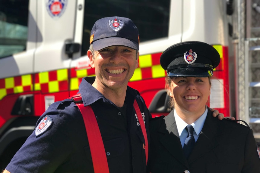 Father and daughter stand side by side in uniform.