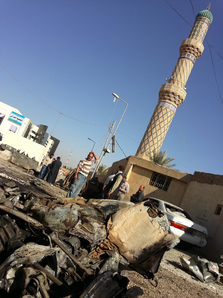 Iraqis look at a destroyed vehicle following the wave of attacks.