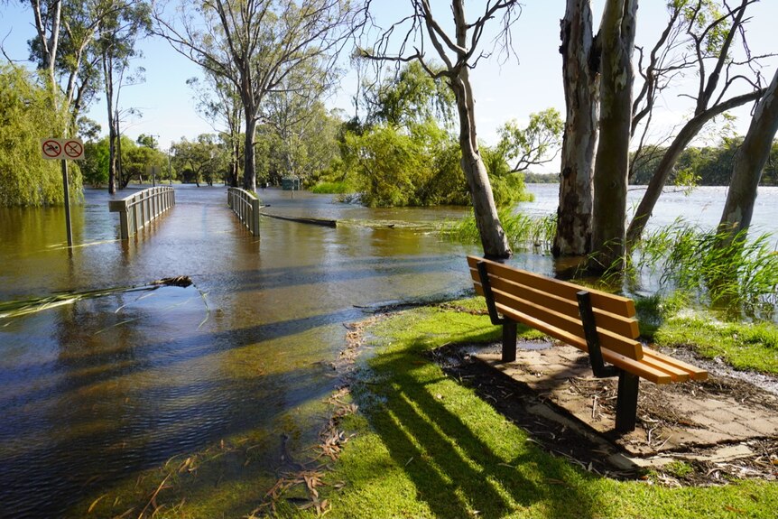 A bench and boardwalk under water near a river