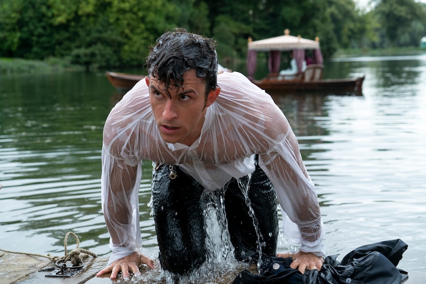 A man getting out of a river wearing a white t-shirt drenched in water