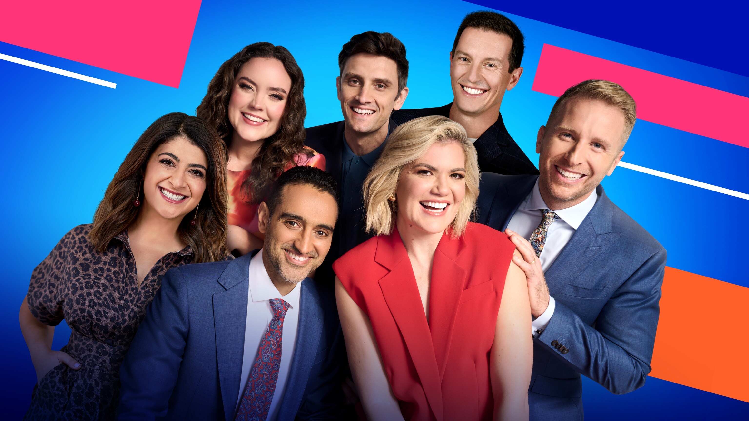 Seven TV hosts all smiling warmly wearing reasonably formal clothing with a blue, pink and orange background