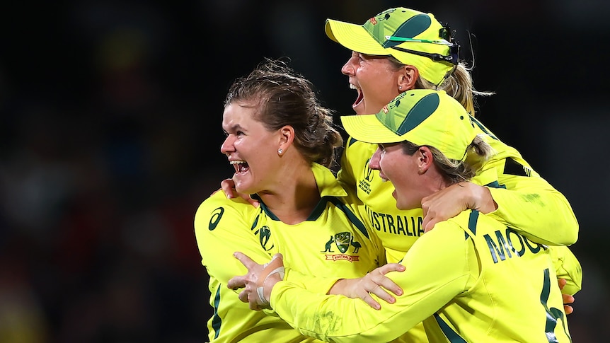 Three Australian female cricketers embrace after winning ODI World Cup.