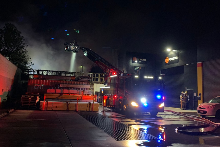 A truck dumps water over the top of a burning dance studio.