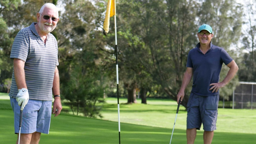 Golfers Andrew Tighe and John Parker stand together on a green at Marrickville Golf Club, April, 2020.