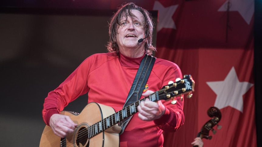 Original Wiggle Murray Cook plays a guitar on stage