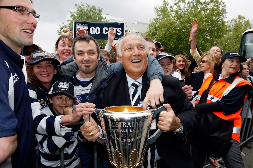 Frank Costa the president of the 2007 AFL premiers holds the cup with fans crowding around during a street parade.