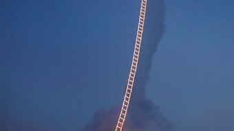 Night sky showing a burning 'ladder' from ground to sky, with balloon attached to top so that it floats.