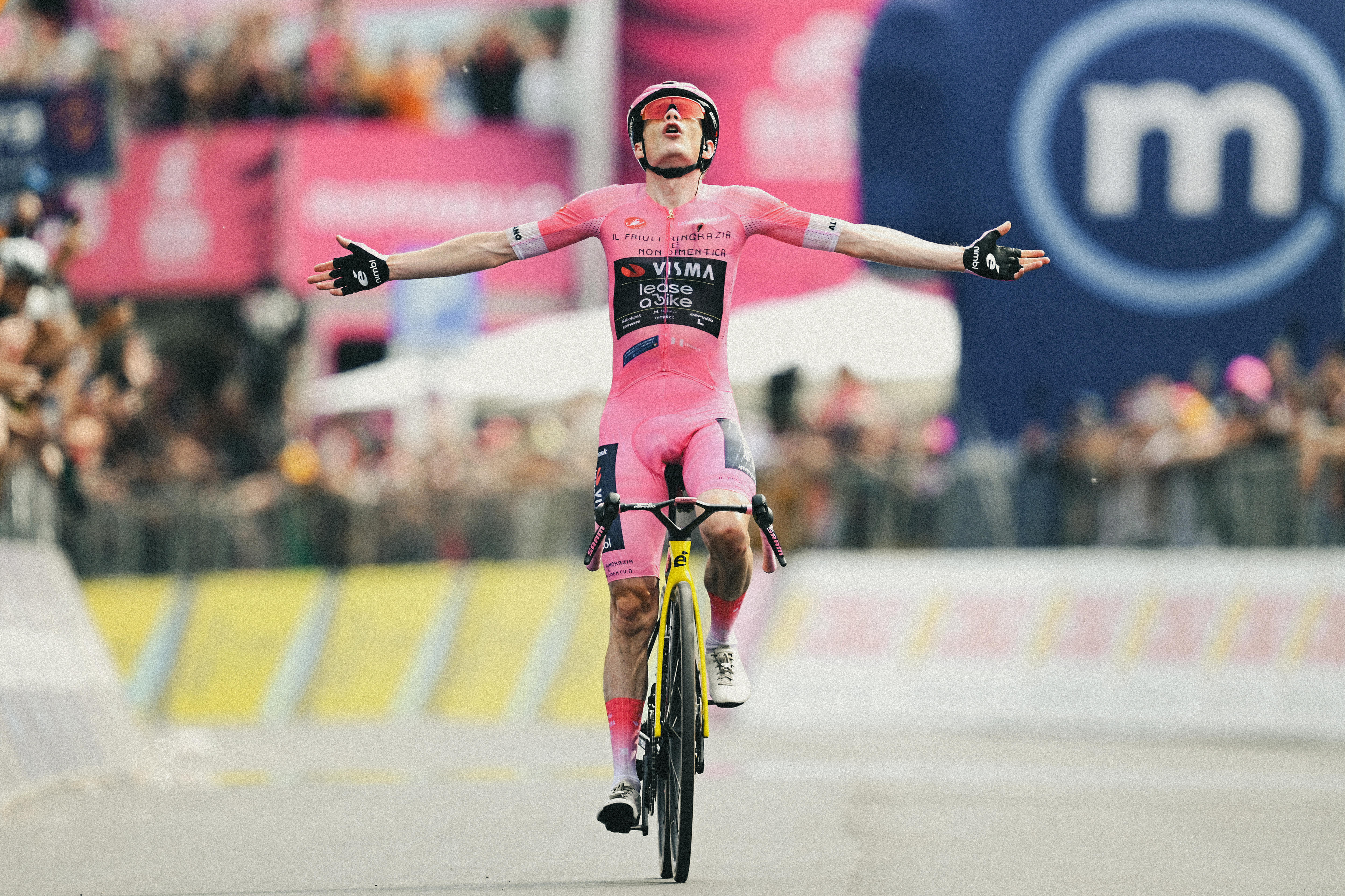 Jonas Vingegaard estende as mãos em vitória enquanto pedala. 