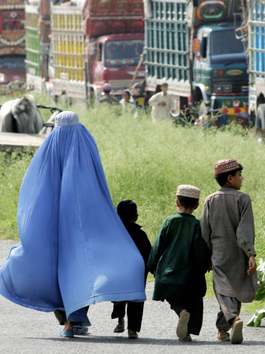 An Afghan refugee woman leads her children to board a truck to leave for Afghanistan from a refugee camp in Islamabad.