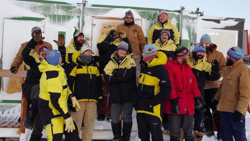 A group of people wearing black and yellow winter coats, and individually designed beanies.