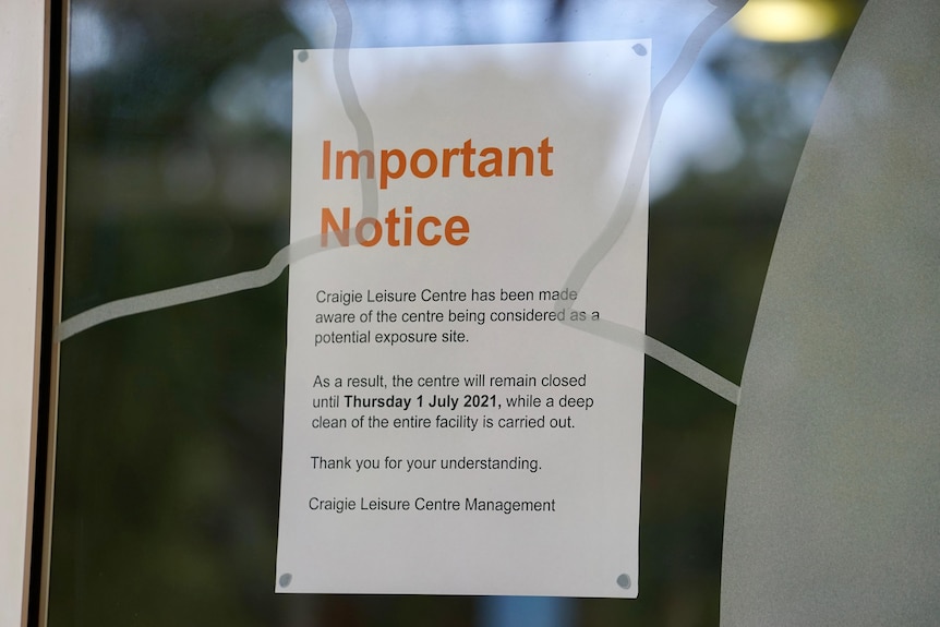 A piece of paper stuck on a glass window that reads "Important Notice" and details COVID-19 transmission.
