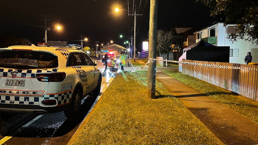 A police car parked in front of a police shelter on a dark street.