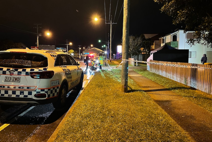 A police car parked in front of a police shelter on a dark street.