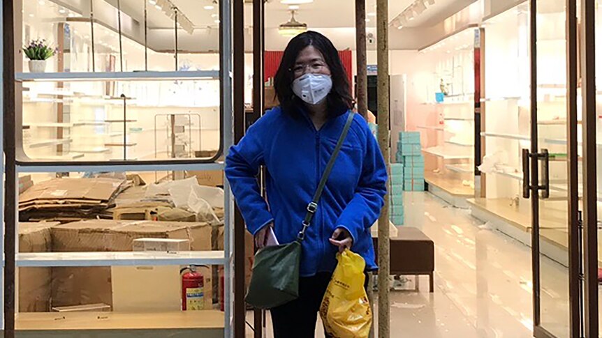 Woman wearing face mask smiles at the camera outside a shop