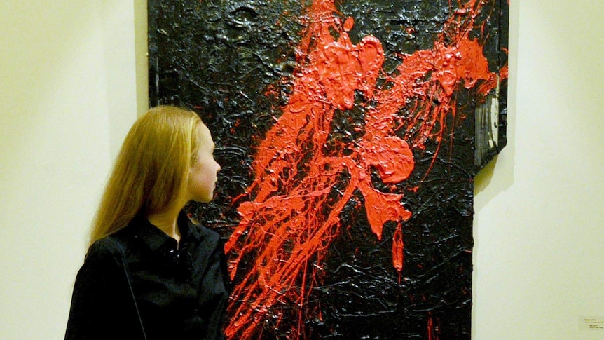 A woman looks at the painting Sex by Sylvester Stallone.