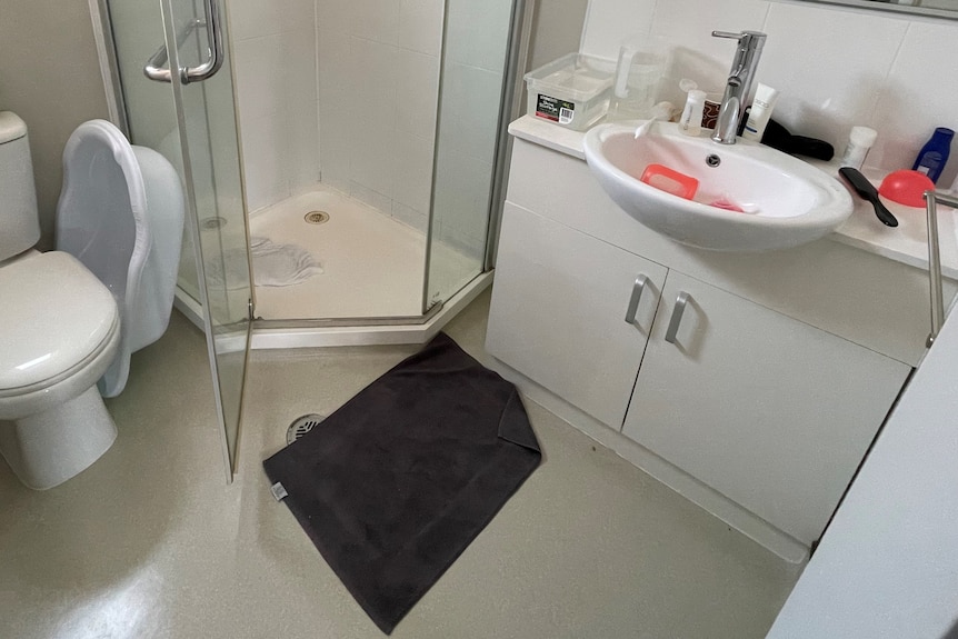 A bathroom with toilet, shower and sink. The sink is filled with baby bottles