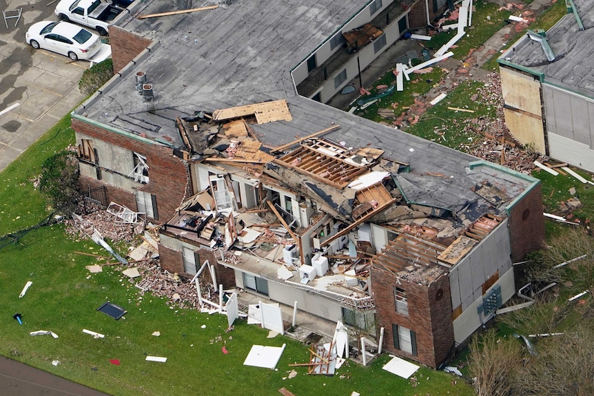 A apartment building is damaged with the roof and part of the walls destroyed.