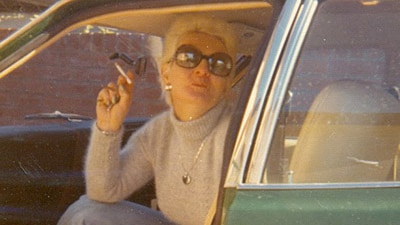 Shirley Finn sitting in a car smoking a cigarette.