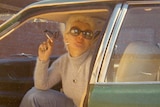Shirley Finn sitting in a car smoking a cigarette.