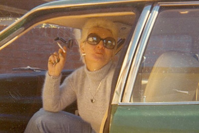 Shirley Finn sitting in a car smoking a cigarette.