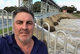 A man standing in front of a weir with rushing water