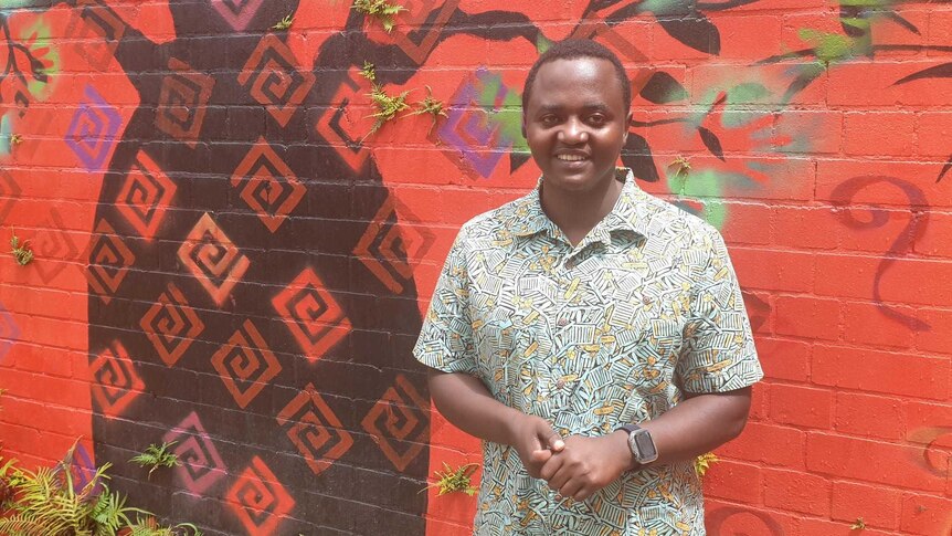 African man Iginas Gasengayire in front of a bright mural