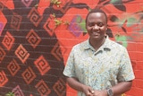 African man Iginas Gasengayire in front of a bright mural