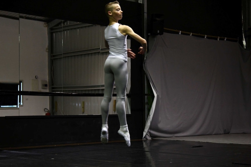 A boy in a ballet uniform pirouettes