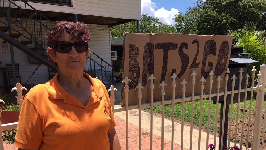 A portrait of Judy Pattel outside her house with the sign 'bats 2 go'.