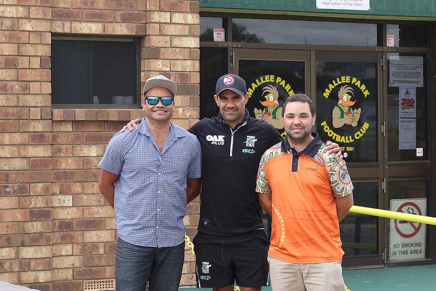 Lindsay stands between his friends Graham Johncock (left) and Scott Kropinyeri underneath the welcome to Mallee Park sign