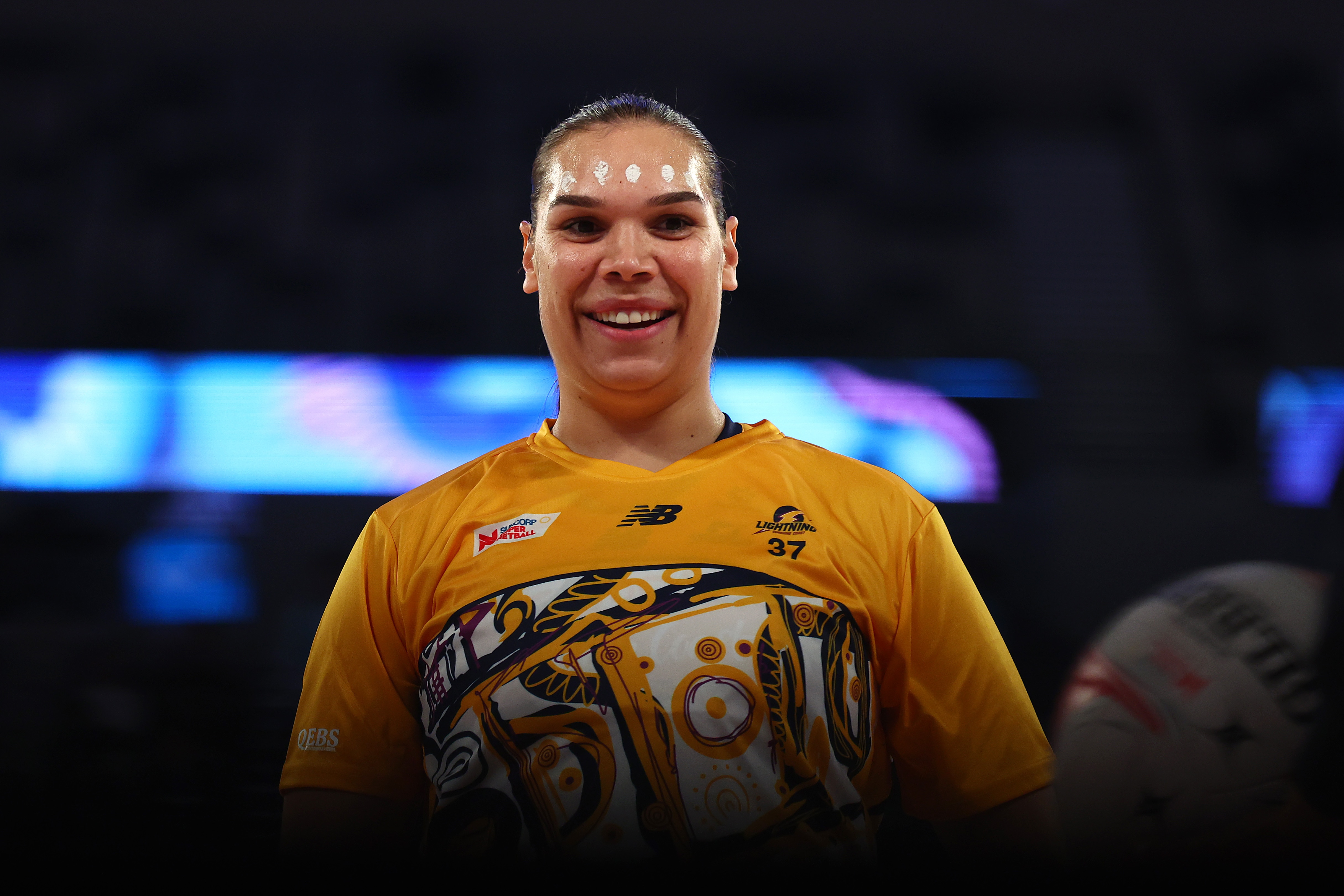 A player has white dots painted across their forehead as they smile and look at the camera