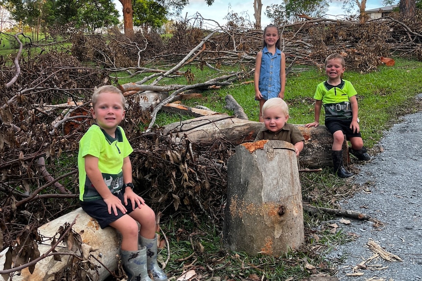 Four smiling children sitting in storm debris