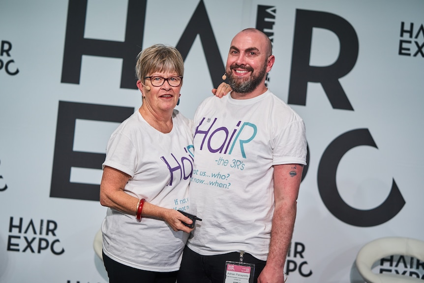 An older woman next to a man wearing matching t-shirts with HaiR written on them.